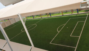 This image is of a large, white building with many windows. It has a green roof, and there is a flagpole in front of it.